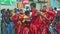 Young boy in red in masquerade costume dances on city street at dominican carnival