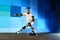 Young boy on roller skates making slide against the blue graffiti wall