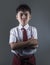 Young boy in school uniform feeling upset and angry looking unhappy and moody posing with folded arms on isolated background