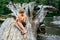 Young boy sitting on a fallen tree trunk, and focusing on to carving a wooden stick for the grill with a small knife