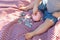 Young Boy Sitting on Picnic Blanket PUtting Coins in Piggy Bank