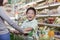 Young boy smiling, sitting in a shopping cart, shopping with mother