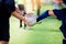 Young boy soccer player kick ball in hands of coach