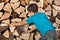 Young boy stacking firewood in the shed