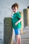 Young boy standing on a wooden rustic dock holding a stick on a warm summer day.