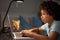 Young Boy Studying At Desk In Bedroom In Evening On Laptop