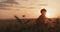 Young boy with a superhero cape stand in a golden wheat field during sunset