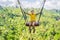 Young boy swinging in the jungle rainforest of Bali island, Indonesia. Swing in the tropics. Swings - trend of Bali