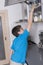 Young boy taking candy from a high kitchen cabinet