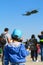 Young boy with toy airplane in hand admiring the Romanian Air Force IAR 330 Puma helicopters performing a demonstration flight