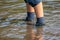 Young boy wading through mud of high tide with blue hiking shoes after a flood has broken the protecting dike