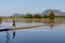 Young boy walking on the flooded rice fields. Mountains at the background at the countryside. Rural landscape. Hpa-An, Myanmar,