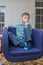 Young boy watch television sitting in blue chair in living room. Kid with blue eyes while watching TV. Ð¡lose up view