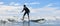 Young boy wearing swimming goggles stable stands on soft board while practicing surfing in beginner`s class