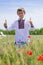 Young boy wearing traditional ukraine clothes in wheat and poppy field