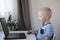 Young boy working on a computer at home. E-lessons, education, programming or english lessons for kids.