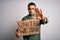 Young brazilian activist man asking for union holding banner with united stand message with open hand doing stop sign with serious