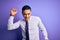 Young brazilian businessman wearing elegant tie standing over isolated purple background Dancing happy and cheerful, smiling