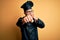 Young brazilian chef man wearing cooker uniform and hat over isolated yellow background Punching fist to fight, aggressive and