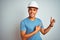 Young brazilian engineer man wearing security helmet standing over isolated white background smiling and looking at the camera