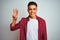 Young brazilian man wearing red shirt standing over isolated white background showing and pointing up with fingers number three