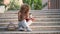 Young Brazilian university student studying and laughing sitting on the stairs.