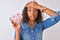 Young brazilian woman holding bowl with marshmallows over isolated white background stressed with hand on head, shocked with shame