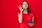 Young brazilian woman using smartphone over red background mouth and lips shut as zip with fingers