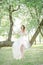 Young bride in beautiful wedding dress sitting on tree outdoors