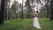 Young bride with bouquet and groom stand in embrace other in forest.