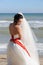 Young bride outdoor portrait in white dress against seascape