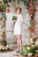 Young bride is standing under the arch of autumn plants