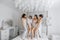 Young bridesmaids in white silk dresses on a bed in the bride\\\'s room.