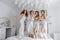 Young bridesmaids in white silk dresses on a bed in the bride\'s room.