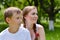 Young brother and elder sister sitting in green summer garden and looking in same direction