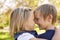 Young brother and sister nose to nose in a park, side view