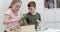 Young brother and sister planting plants in a wooden box carefully arranging the soil around the green leafy plant -