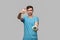 Young brunet man pointing with finger at the alarm isolated over grey background. Hurry up