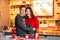 Young brunette asian woman and white man in Christmas sweaters making cookies together on the kitchen. Lights background