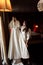 The young brunette bride in a dressing gown straightens a wedding dress in the hotel room. Attractive bride touching and