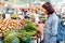 Young brunette choosing and picking some vegetables at the grocery market