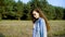 Young brunette in denim posing sensually on background of trees in field.