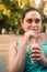 Young brunette enjoys her iced lemonade in the park