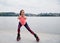 Young brunette fit slim woman in kangoo jumps, training in front of city lake in summer. Fitness trainer, wearing dark blue