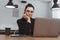 Young brunette freelancer woman in black suit procrastinate, working on laptop in empty cafe