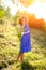 A young brunette girl in a blue dress posing with a bouquet of wild flowers in a park in the rays of a bright sun