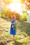 A young brunette girl in a blue dress posing with a bouquet of wild flowers in a park in the rays of a bright sun