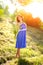 A young brunette girl in a blue dress posing with a bouquet of wild flowers in a park in the rays of a bright sun