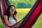 Young brunette girl lies in a hammock and talks on the mobile phone.