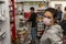 A young brunette girl in a protective medical mask looks at the camera and stands in line at the cash register in a supermarket.